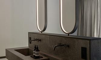 A modern bathroom with an elegant stone sink. Two stylish, round lights hang above the sink.