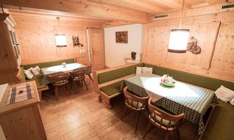 A cozy room with wooden walls and a large table. Red and green seating areas invite you to linger.