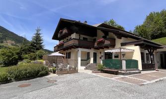 A charming house amidst mountains with a balcony and flowers. The well-kept garden and the parking space give the property an inviting atmosphere.