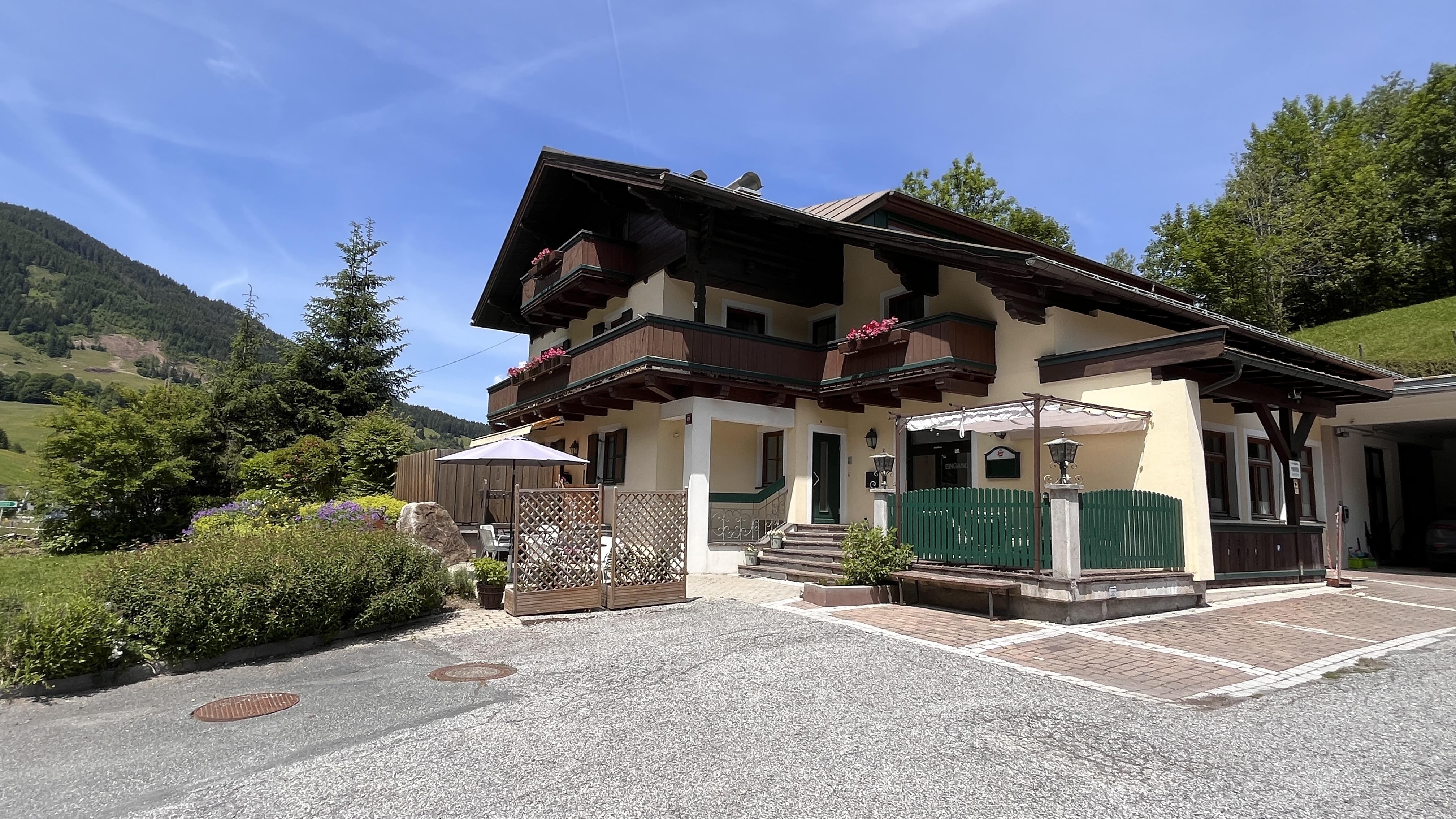 A charming house amidst mountains with a balcony and flowers. The well-kept garden and the parking space give the property an inviting atmosphere.