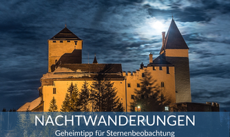 A historic castle under a dramatic night sky with clouds and moonlight. A hint at night hikes for stargazing.