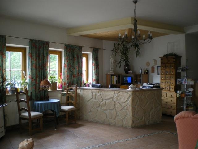 A cozy room with a stone bar and bright windows. Chairs and decorations create an inviting atmosphere.