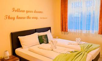 A cozy bedroom with a double bed and decorative towels. On the wall is the motivational phrase "Follow your dreams. They know the way."
