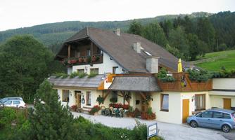 A charming guest house with a balcony and green surroundings. Surrounded by trees, it offers a cozy atmosphere for visitors.