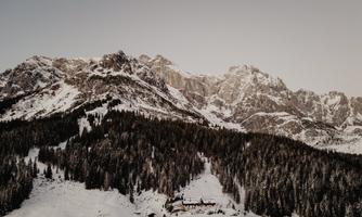 An impressive mountain landscape with snow-covered peaks and dense forests. The calm atmosphere radiates winter magic.