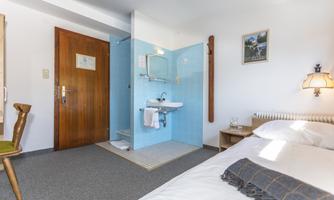 A cozy hotel room with a double bed and a modern bathroom. The walls are light and the room has a friendly atmosphere.