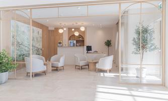 A modern reception area with bright walls and elegant furniture. There are plants and soft lighting that create an inviting atmosphere.