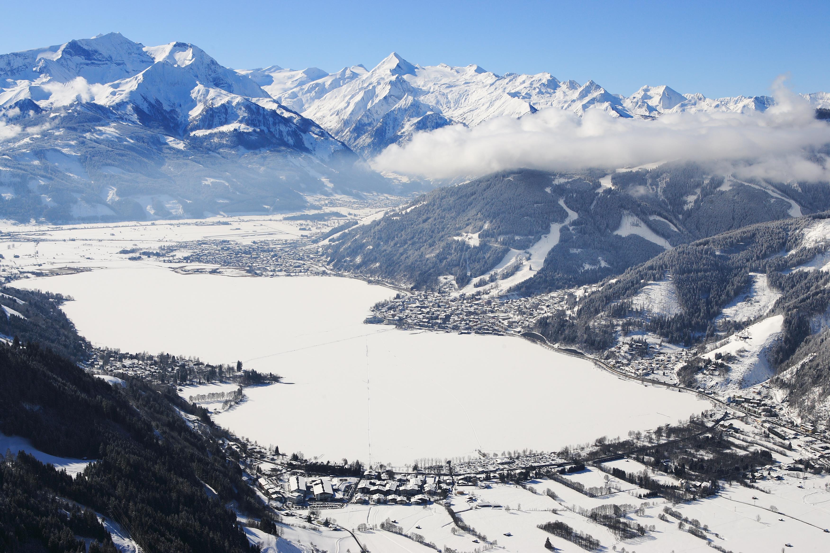 A picturesque lake surrounded by snow-capped mountains. The sky is clear and the landscape exudes tranquility.