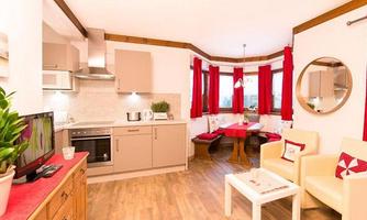 A cozy living kitchen with modern furniture and red curtains. The room is bright and inviting, ideal for relaxation and enjoyment.
