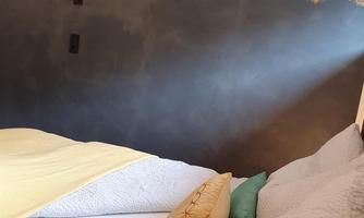 A cozy bedroom with a modern, simple design.  
Golden mandala patterns can be seen on the wall, adding a special touch to the room.
