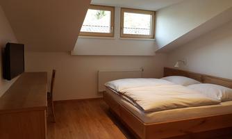 A cozy bedroom with a double bed, wooden furniture, and skylights. The room has a warm and inviting atmosphere.