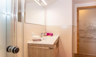 A modern bathroom with a large mirror and a wooden vanity. The walls are bright and the decor is minimalist and clean.