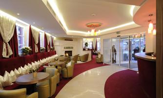An elegant reception area with comfortable seating and warm lighting. The walls are decorated with red curtains, the design creates an inviting atmosphere.