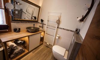 A modern-designed bathroom with wooden shelves and an elegant sink. There is a large mirror and towels neatly stored.