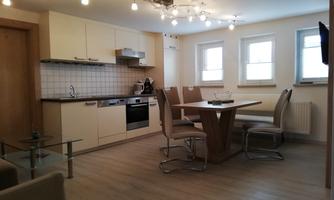 Modern kitchen with a dining area that includes a large table and stylish chairs. Bright walls and light sources create an inviting atmosphere.