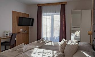 A modern room with a large bed and a television. The window lets in plenty of daylight and provides a pleasant atmosphere.
