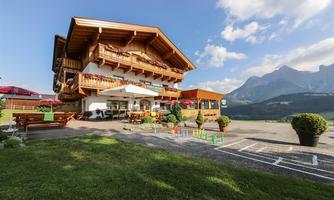 A charming wooden house with balconies and a terrace in the mountains. The garden area is inviting with play opportunities and a beautiful view of the landscape.