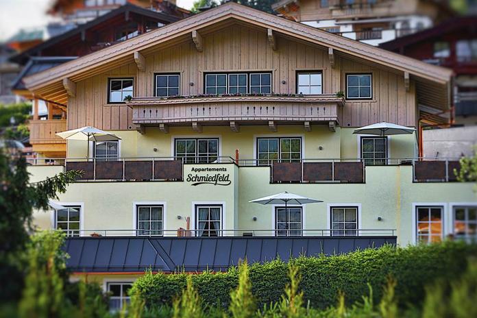 A charming building with several balconies and sun umbrellas. It houses the "Schmiedl" apartments in a picturesque setting.