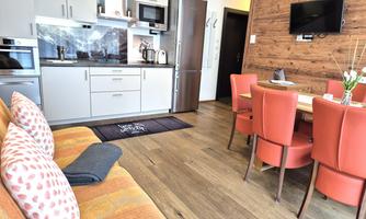 A modern kitchen with a dining area and a cozy seating corner. The space is designed to be bright and friendly.