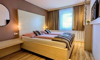 A modern bedroom with a double bed and wooden floor.