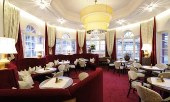 An elegant restaurant with red walls and modern furniture. Large windows let in plenty of natural light and create an inviting atmosphere.