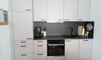 A modern kitchen with bright cabinets and a dark countertop. On the side are cooking utensils and appliances.