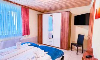 A cozy bedroom with a double bed and a large wardrobe. The room has light walls and a television on the wall.