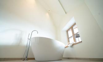 A modern bathroom with an elegant, freestanding bathtub. Large windows provide plenty of daylight and an inviting atmosphere.