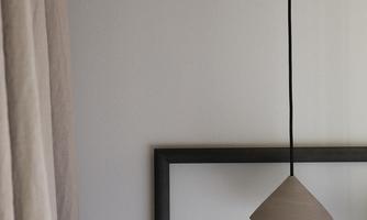 A minimalist interior design with a hanging lamp. In the background, there is a black picture frame and a curtain.