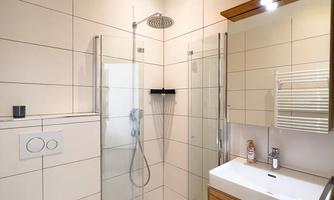 A modern bathroom with a glass shower and a stylish wooden sink. The walls are tiled in light colors, giving the space a spacious feel.