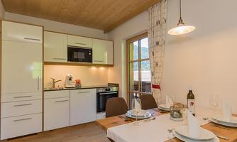 A modern kitchen with bright furniture and a dining area. The window offers a view of a beautiful landscape.