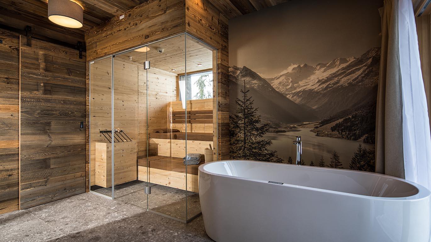 A modern bathroom with a freestanding bathtub and a glass shower. On the wall, there is a large landscape painting depicting mountains and lakes.