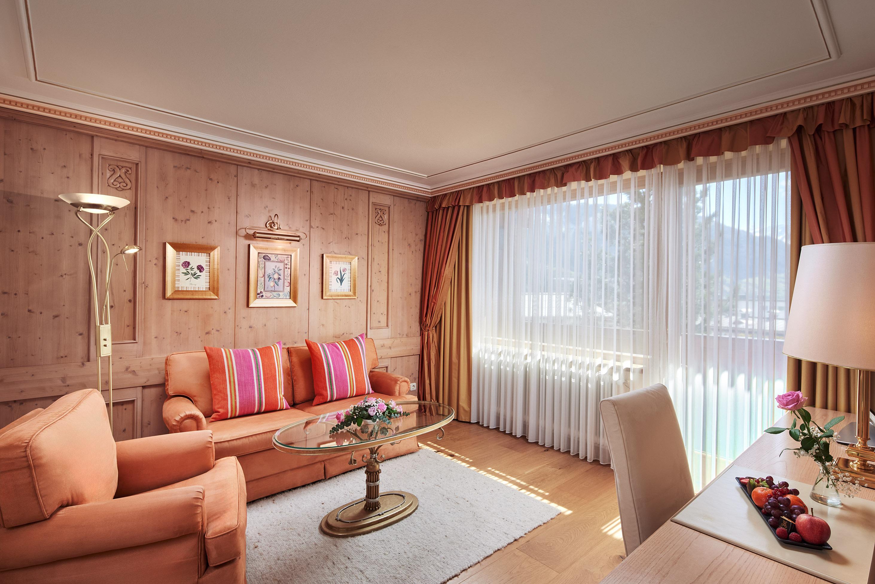 An elegant living room with a cozy sofa and a coffee table. The large windows let in plenty of light and offer a beautiful view outside.