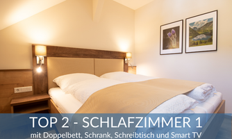 Cozy bedroom with a double bed, wardrobe, and workspace. The room is modernly furnished and has a smart TV.