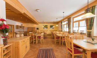 An inviting dining area with wooden chairs and tables. Large windows provide plenty of daylight and a pleasant atmosphere.