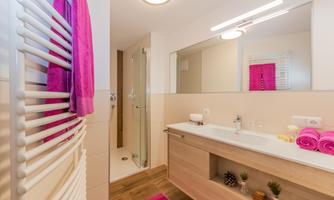 A modern bathroom with a large mirror and a shower. Towels in vibrant colors create a fresh look.