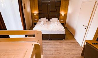 A cozy room with a double bed and a bunk bed. Bright walls and warm wood give the room an inviting atmosphere.