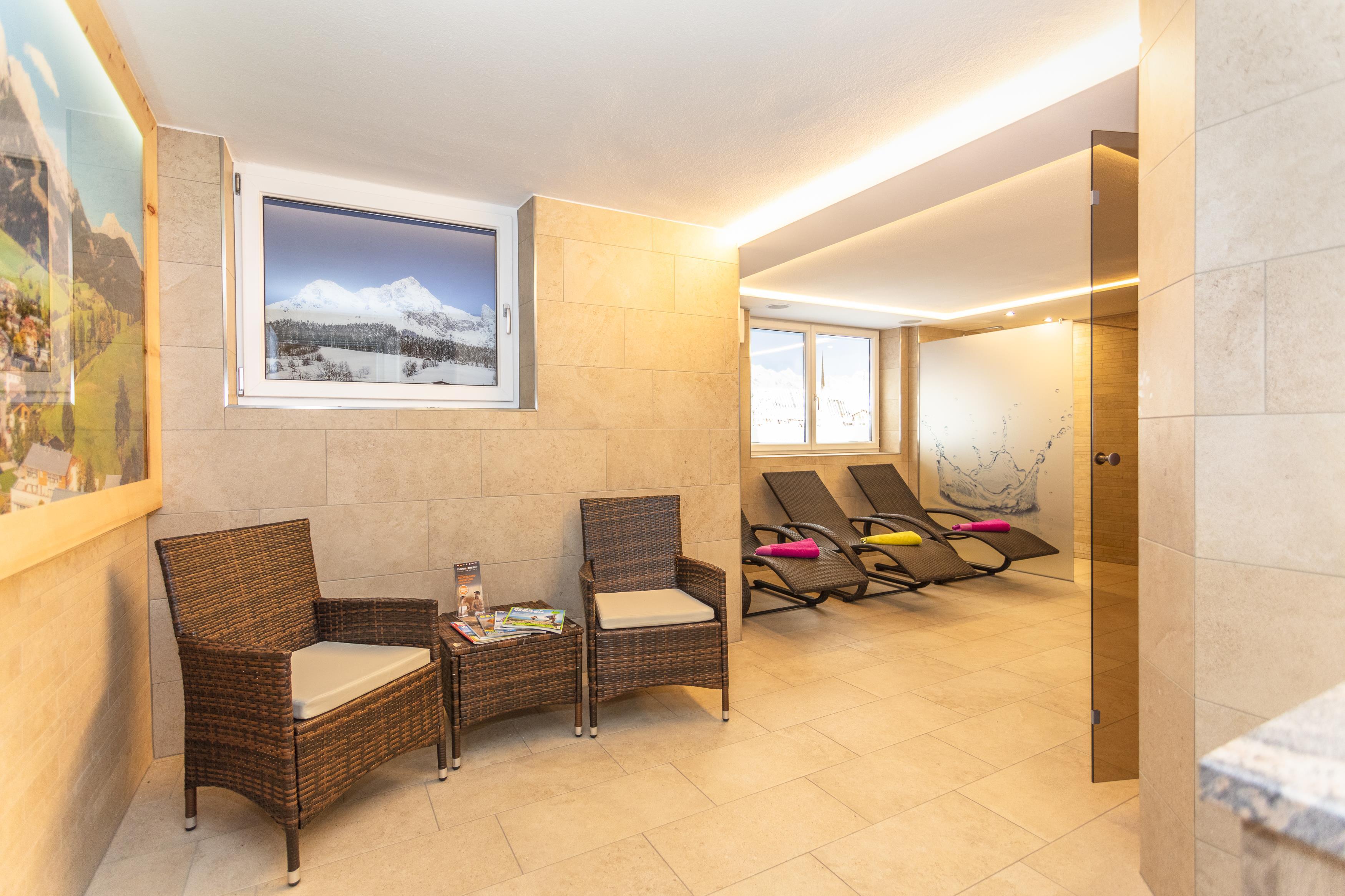 A tranquil wellness area with cozy loungers and stylish furniture. Large windows provide a view of the mountains.