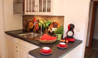A modern kitchen with a sink and an attractive background design featuring fresh fruits and vegetables. On the counter are red mugs and a few fresh ingredients.
