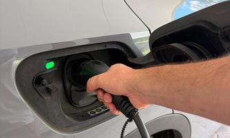 An electric car is currently being charged. The charging socket glows green, indicating that the charging process is active.
