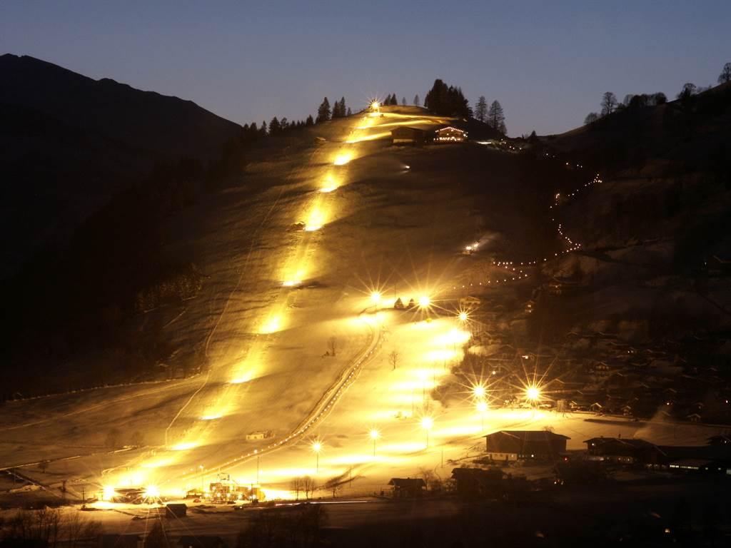 A lit ski slope at night. The lights create a festive atmosphere and invite you to ski.