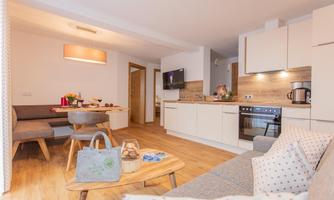 A modern apartment with an open kitchen and a cozy living area. Bright colors and wooden floors create an inviting atmosphere.