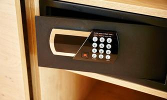 An electronic safe with a keypad that is open. It is located in a wooden cabinet.