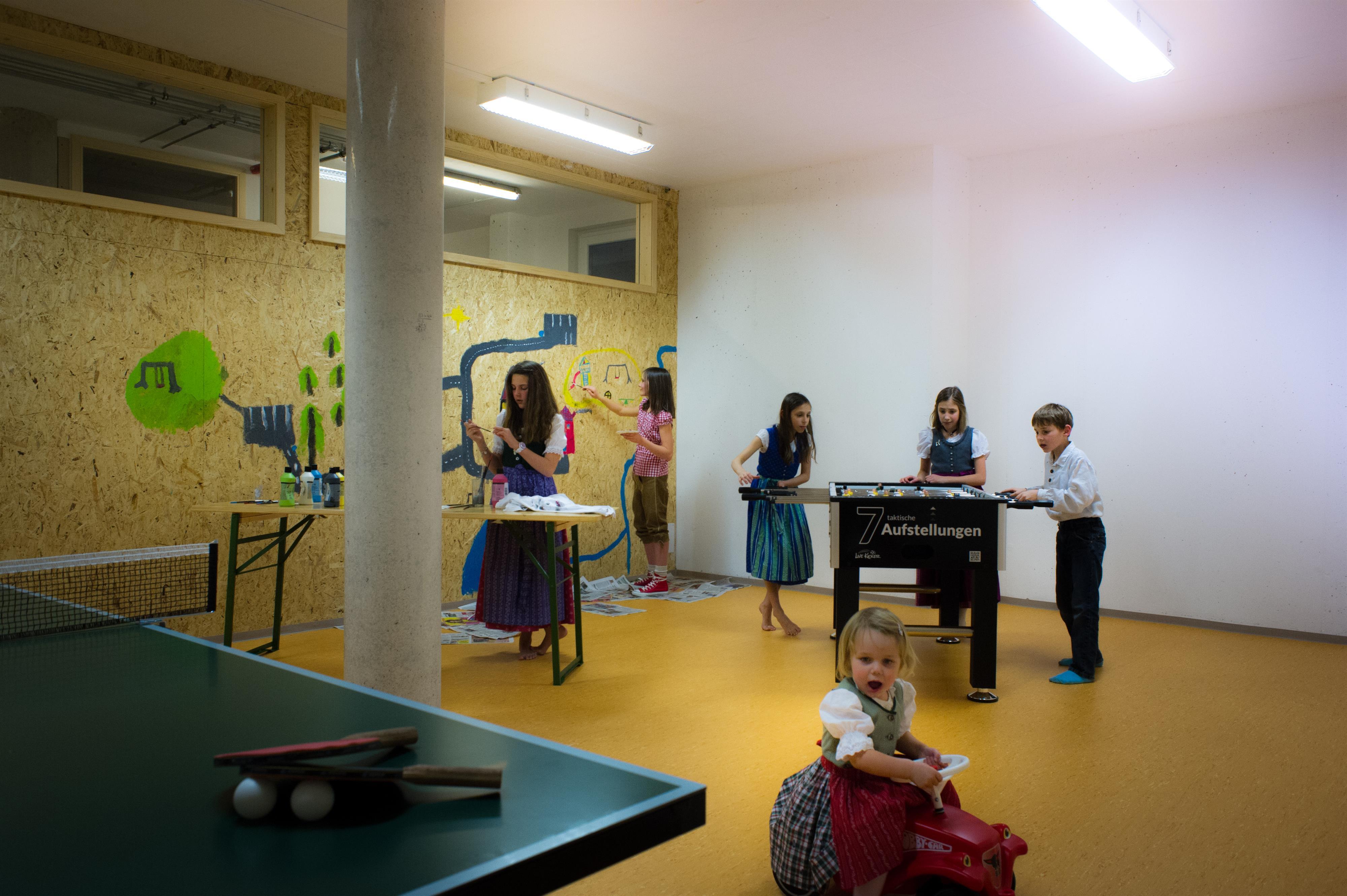 A playroom with children playing and having fun. There is a foosball table and various activities.