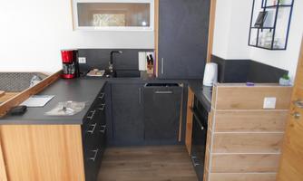 A modern kitchen with wood and dark cabinet fronts. It is well equipped with appliances and has a bright, inviting atmosphere.
