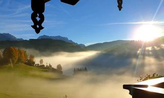 A beautiful view of a misty landscape in the mountains. The sun shines through the clouds, creating a peaceful atmosphere.