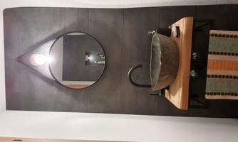 A modern bathroom with a stylish stone sink and a round mirror. The walls are dark, and the lighting creates a pleasant atmosphere.