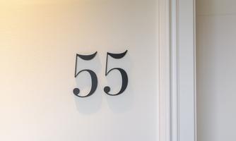A white wall with the numbered depiction "55" in black lettering. The digits are elegantly and clearly designed.