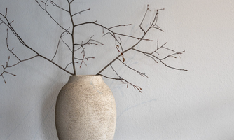 A minimalist vase stands on a table. Inside are dry branches that create a calm atmosphere.