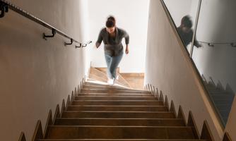 A person is running up the stairs. The room is bright with a mirror on the wall.